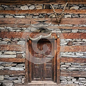 Old house door, wall decorated with horns. Nakthan, Parvati valley, Himachal Pradesh, India