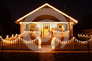 An old house with front porch and picket fence decorated with Christmas lights