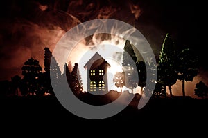 Old house with a Ghost in the forest at night or Abandoned Haunted Horror House in fog. Old mystic building in dead tree forest. T