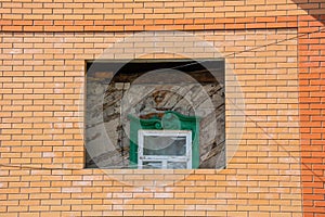 Old house with old green window inside brick and new house. Home under construction. Renovation