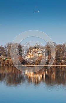 Old house over water. Reflection of a house in the river. Landscape with the house and trees displayed in the water_
