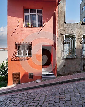 Old house painted in orange, and wrought iron windows, at a cobblestone street, Balat district, Istanbul, Turkey