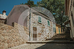 Old house with rough stone wall in an alley with steps
