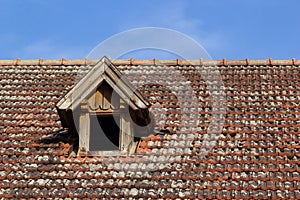 Old house with tile roof on the background of the sky. Texture, roof repair in vintage style