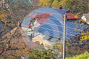 An old house in Ukraine with a red tiled roof lined with solar panels. Photovoltaic panels on the roof. Saving electricity