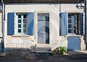 Old house white facade with shutters and entrance door painted in blue