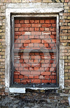 Old house window sealed with red bricks