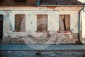 An old house with windows closed with wooden rickety shutters in Kuldiga, Latvia