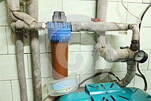 Old household filter and pipes in water supply system of house. Dirty rusty filter for water purification. Multi stage