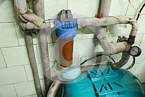 Old household filter and pipes in water supply system of house. Dirty rusty filter for water purification. Multi stage