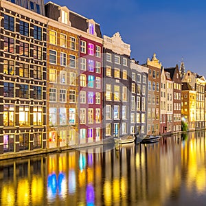 Old houses of Amsterdam. The houses stand in the water and have a beautiful reflection. Touristic district Damrak. These houses