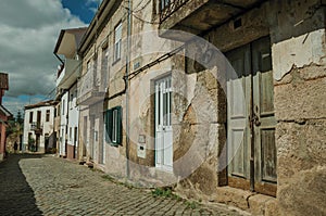 Old houses with cracked plaster wall in an alley with pedestrian