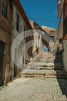 Old houses in deserted alley with steps on slope photo