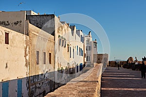 Old houses in Essaouira Morocco in the sunset light with shadows and strolling promenade