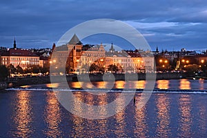 Old houses in Prague at the river Vltava in the dawn with reflections in the water.