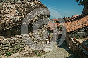 Old houses and stone wall with big rock in Monsanto