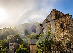 Old houses under the fog, in the medieval village of Saint-Cirq-Lapopie in the Lot in Occitanie, France