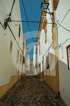 Old houses with whitewashed wall in alley on slope
