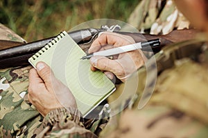 Old hunter loading his gun ans taking notes