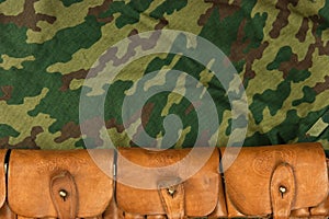 Old hunting cartridges and bandoleer on camouflage background