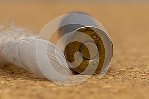 Old hunting cartridges are scattered on a textured background, there is a bird`s feather, close-up, selective focus. Concept: bird