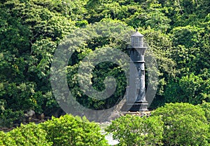 An old, inactive black lighthouse in the Panama Canal