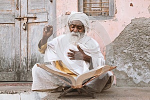 Old indian sadhu reading scriptures.