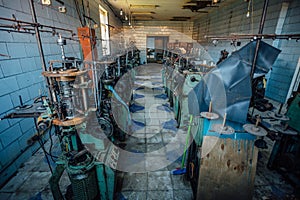 Old industrial machine tools in abandoned workshop. Rusty metal equipment in abandoned factory