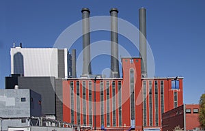 Old industrial power plant with new modern buildings against a blue sky, exterior view image