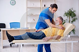 Old injured man visiting young male doctor chiropractor