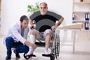 Old injured man visiting young male doctor traumatologist photo