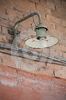 Old insdustrial lamp on the red-brick wall