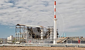 Old installation of a refinery smokestack under cloudy sky