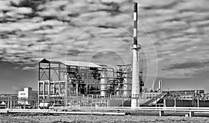 Old installation of a refinery smokestack under cloudy sky