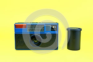 Old instamatic camera and its lens isolated on a yellow background