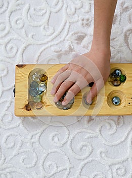 Old intelligence games, wooden mancala game, a person playing mancala