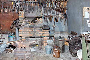 An old iron anvil against the background of the interior of a blacksmith shop with a brick oven