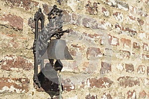 Old iron bell placed on a brick wall