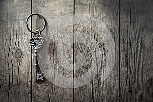 Antique iron key hanging on a nail on wooden boards