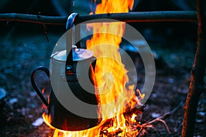 Old Iron Camp Kettle Boils Water On A Fire In Forest. Bright Flame Fire