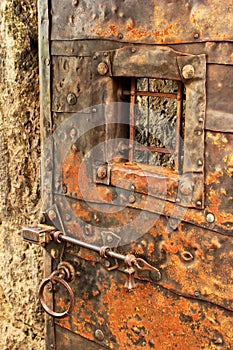 Old iron-clad door with grilled window, bar lock and ring handle