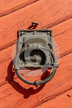 Old iron door knocker on a red wooden door