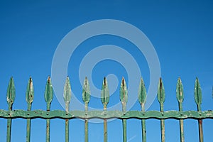 Old iron fence on blue sky - vintage wrought metal spikes -