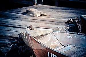 Old iron frayed and shabby boat noses tied to wooden dock and cat