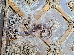 An old iron handle on an iron door decorated with flowers of the old temple
