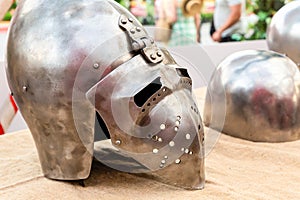 Old iron helmet with visor protection of medieval warrior rider lies on a wooden table