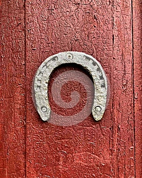 Old iron horseshoe on a wooden red painted door background.