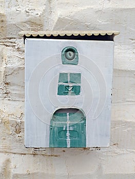 Old mailbox painted blue and green on white wall. Antique metal letter box. Old iron mailbox on a brick wall