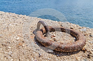 Old iron mooring cleat on a concrete pier