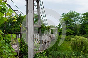 Old iron non-functioning suspension bridge over a dried river side view.